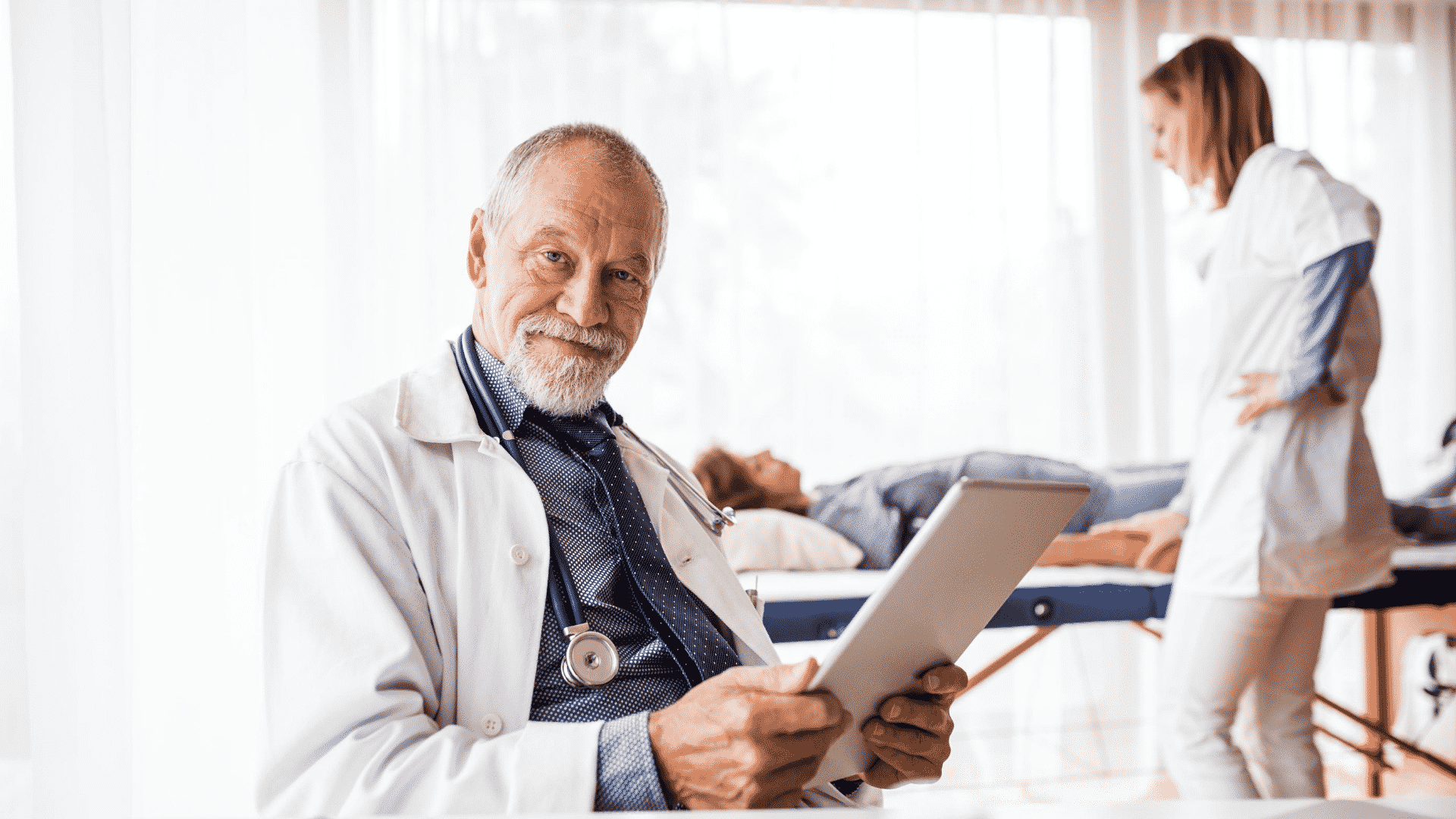 older medical doctor reviewing charts on a tablet