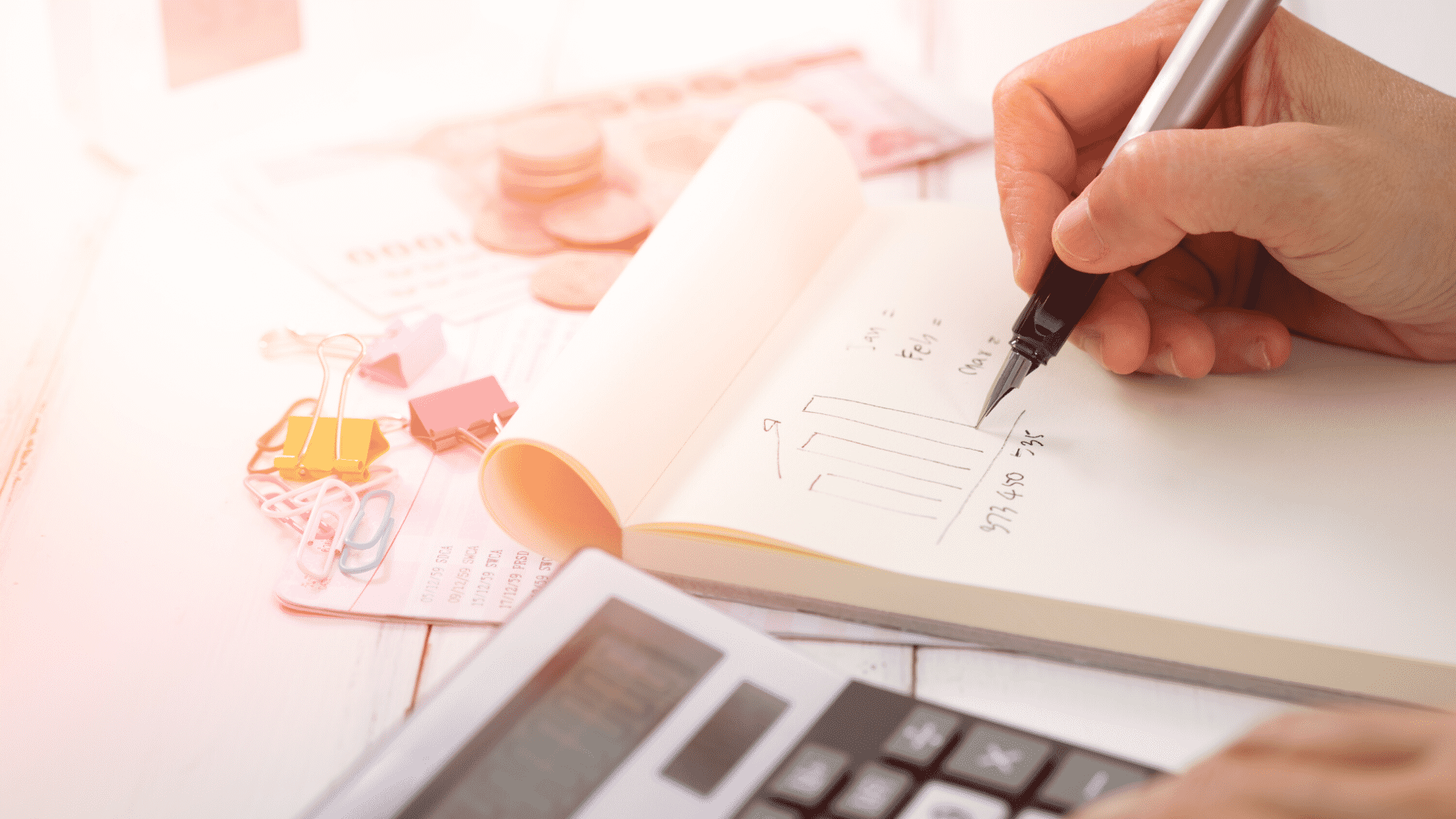Person doing accounting with a calculator, pen and paper
